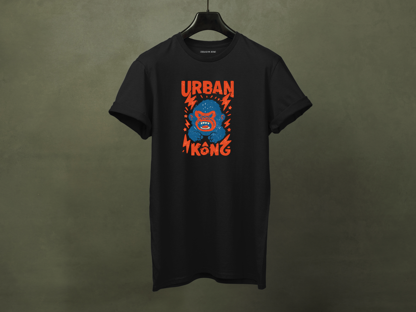 Hanged black streetwear t-shirt with a graphic of vibrant blue cartoon gorilla head, surrounded by red lightning bolts and stars, and the 'URBAN KONG' text in distressed red.