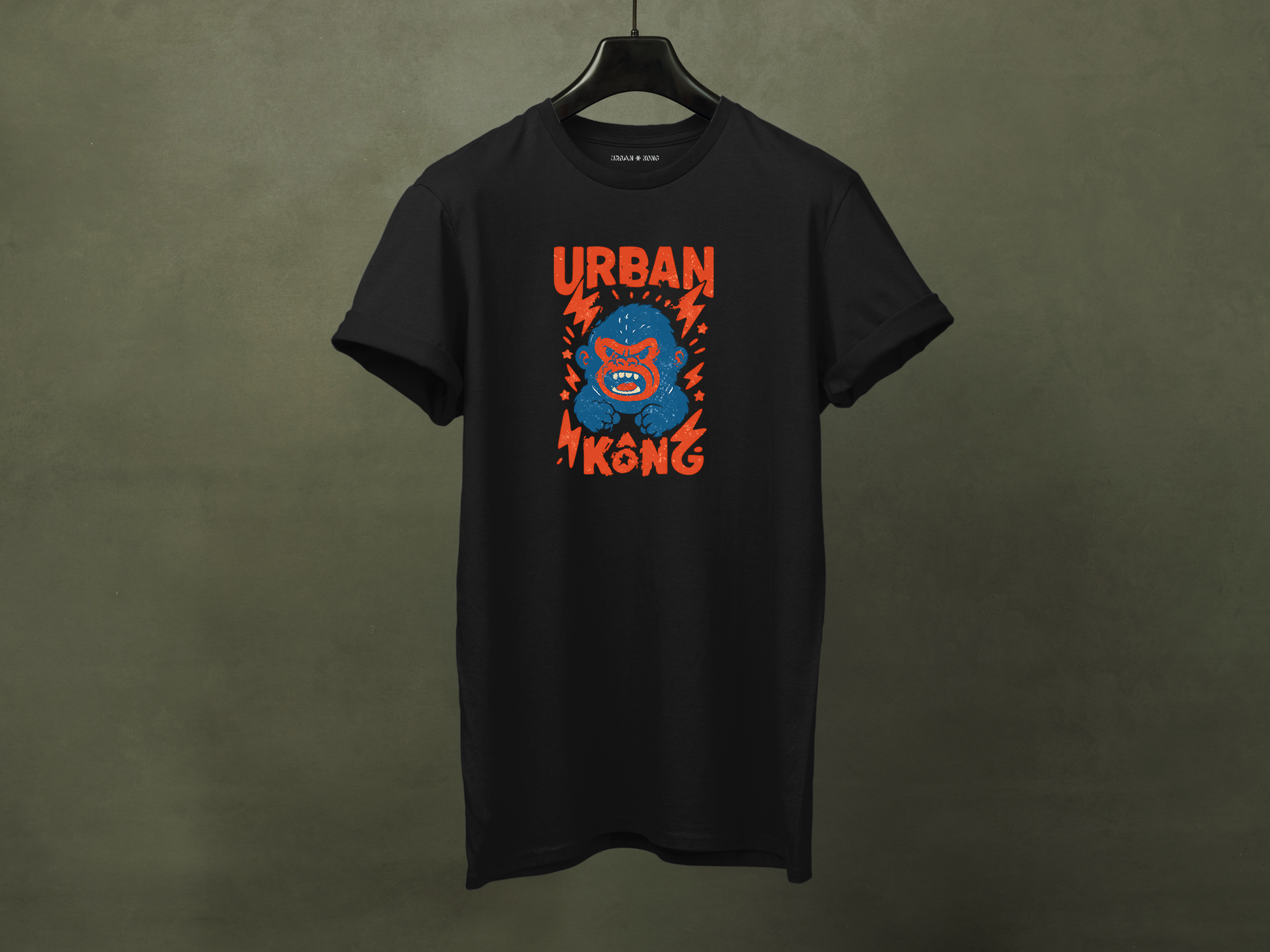 Hanged black streetwear t-shirt with a graphic of vibrant blue cartoon gorilla head, surrounded by red lightning bolts and stars, and the 'URBAN KONG' text in distressed red.
