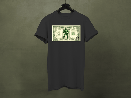 Black t-shirt with a graphic of a superhero on a dollar bill design, hanging against a dark background.