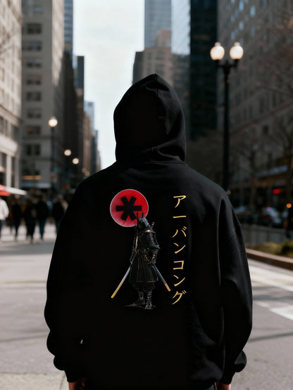 Person wearing a black hoodie with a graphic design on the back in an urban setting