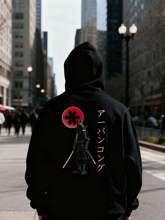 Person wearing a black hoodie with a graphic design on the back in an urban setting