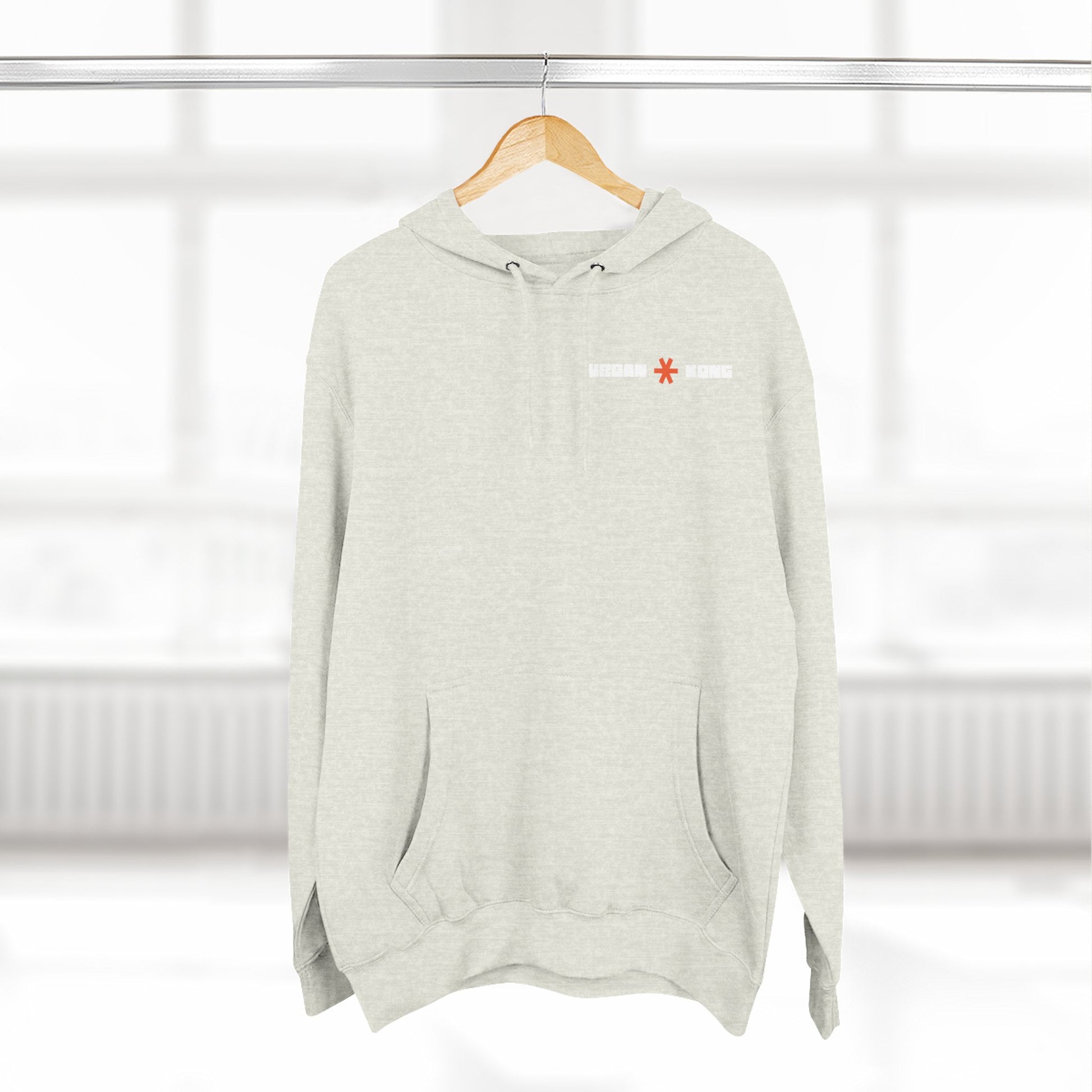Light gray hoodie with a small red and white logo on a wooden hanger against a white background.