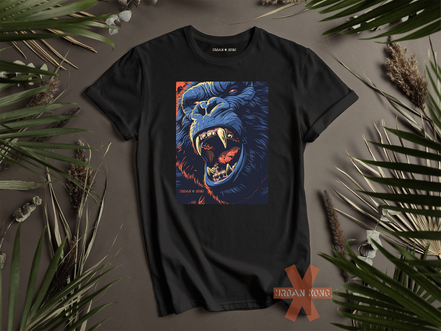 T-shirt nera appoggiata su una superficie decorata con foglie, con una grafica centrale che raffigura un gorilla ringhiante in stile illustrato, dai toni blu e arancio, appartenente al brand Urban Kong.