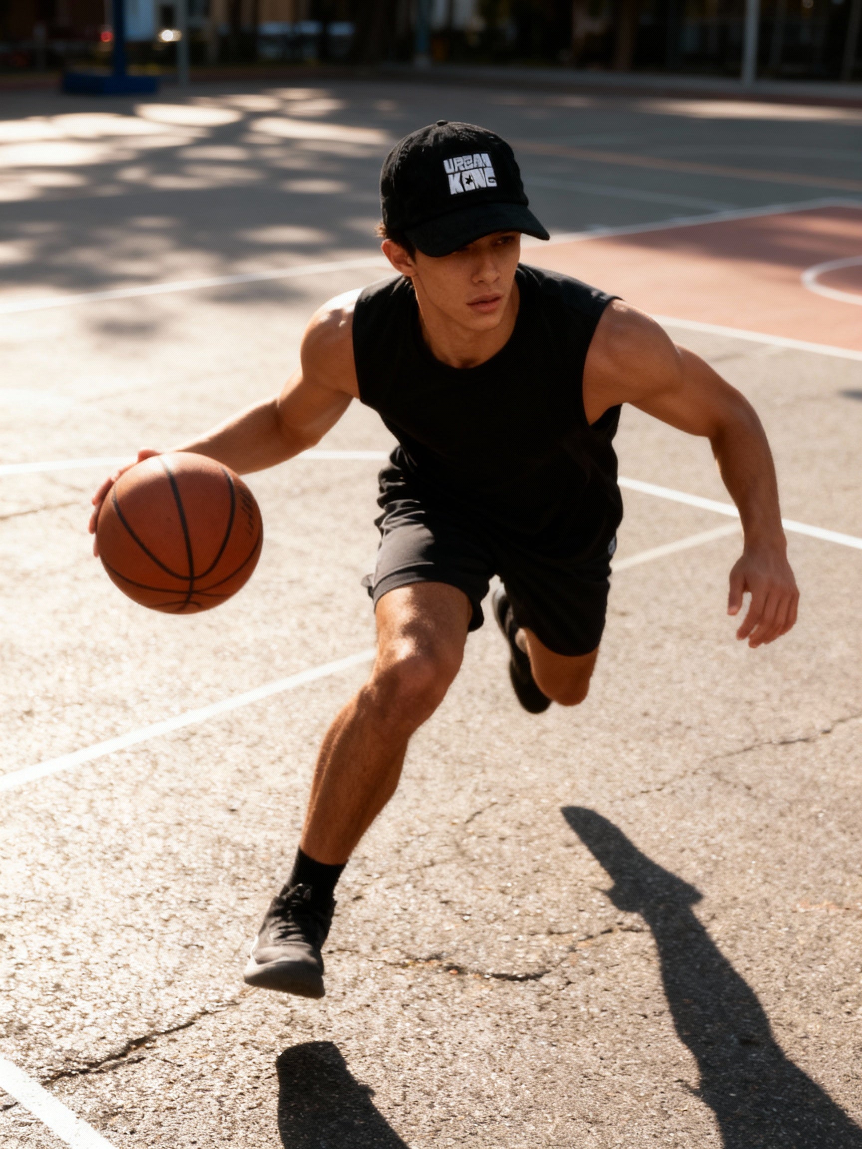 Man playing basketball on an outdoor court wearing a black cap and sleeveless shirt.